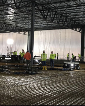 B&B Concrete workers in yellow safety vests lay concrete inside of a warehouse