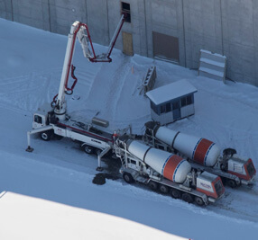 two concrete mixers are hooked up to another truck that is siphoning concrete into a building for B&B Concrete services