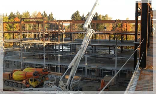 Concrete installation at a new construction site in Michigan with two concrete mixing trucks